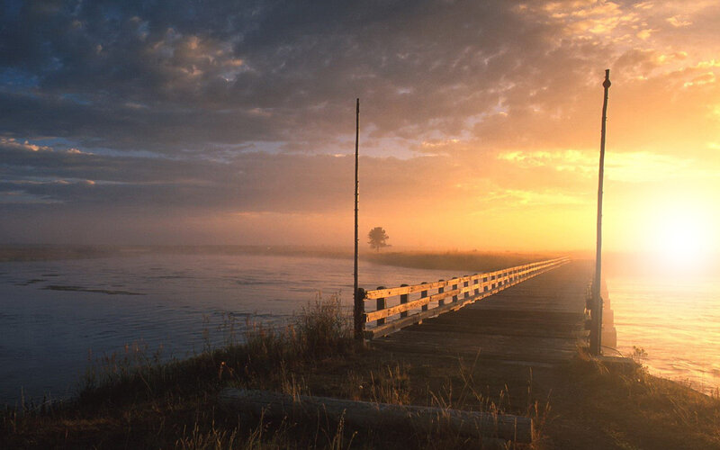 Sunrise over a misty lake pier