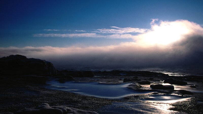 Sunrise over a misty rocky shore