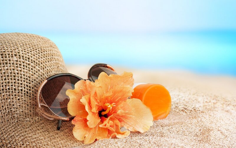 Sunscreen and Flower on Sand
