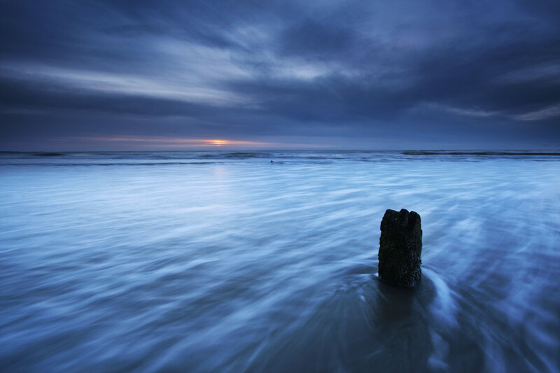 Sunset at the beach with a post