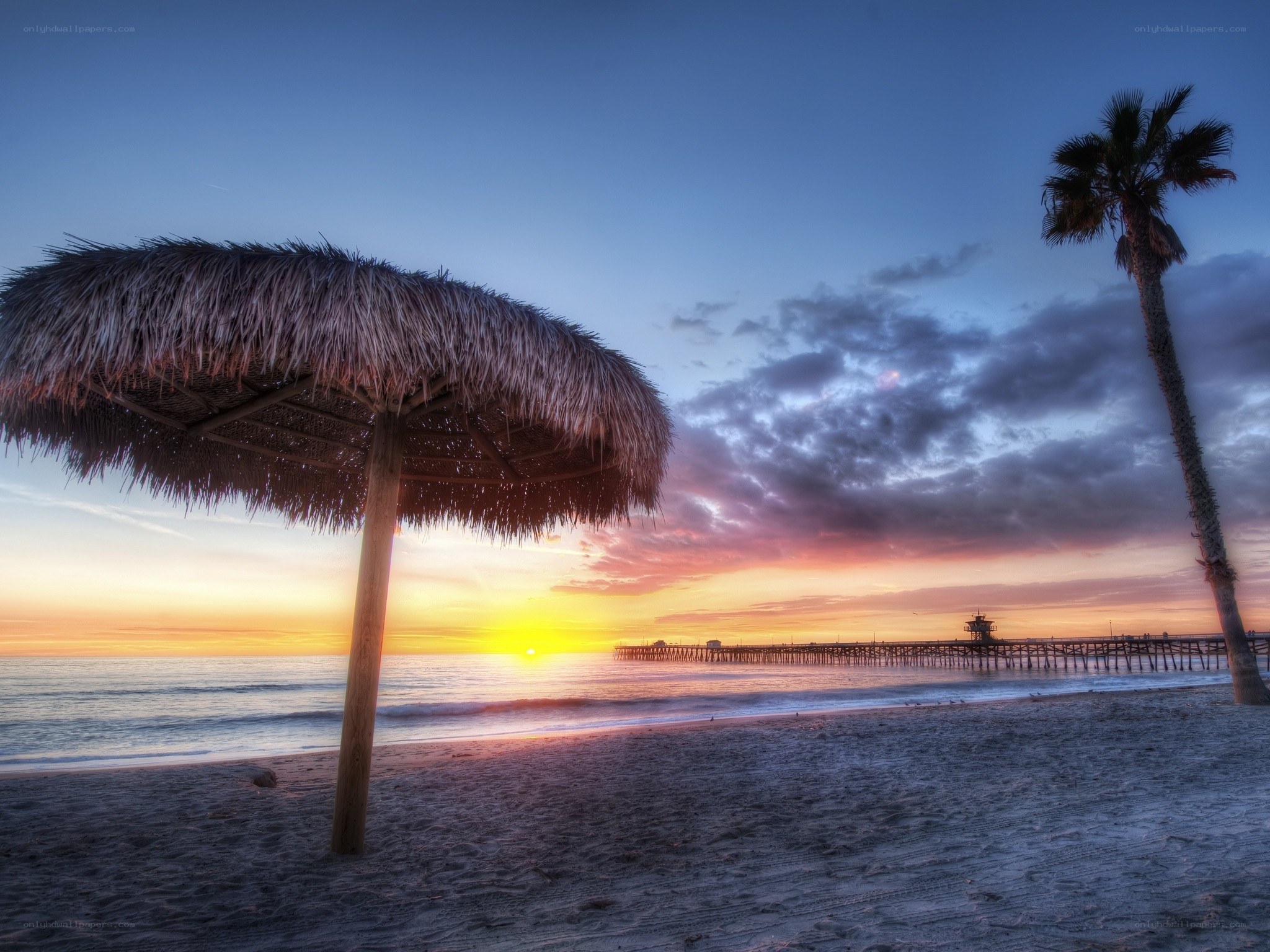 Sunset at the beach with a thatched umbrella