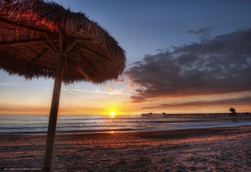 Sunset at the beach with a thatched umbrella