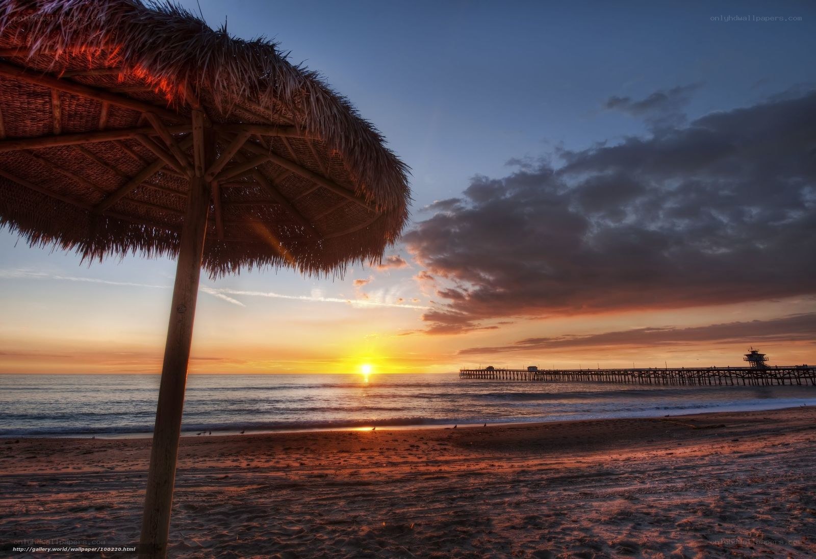 Sunset at the beach with a thatched umbrella