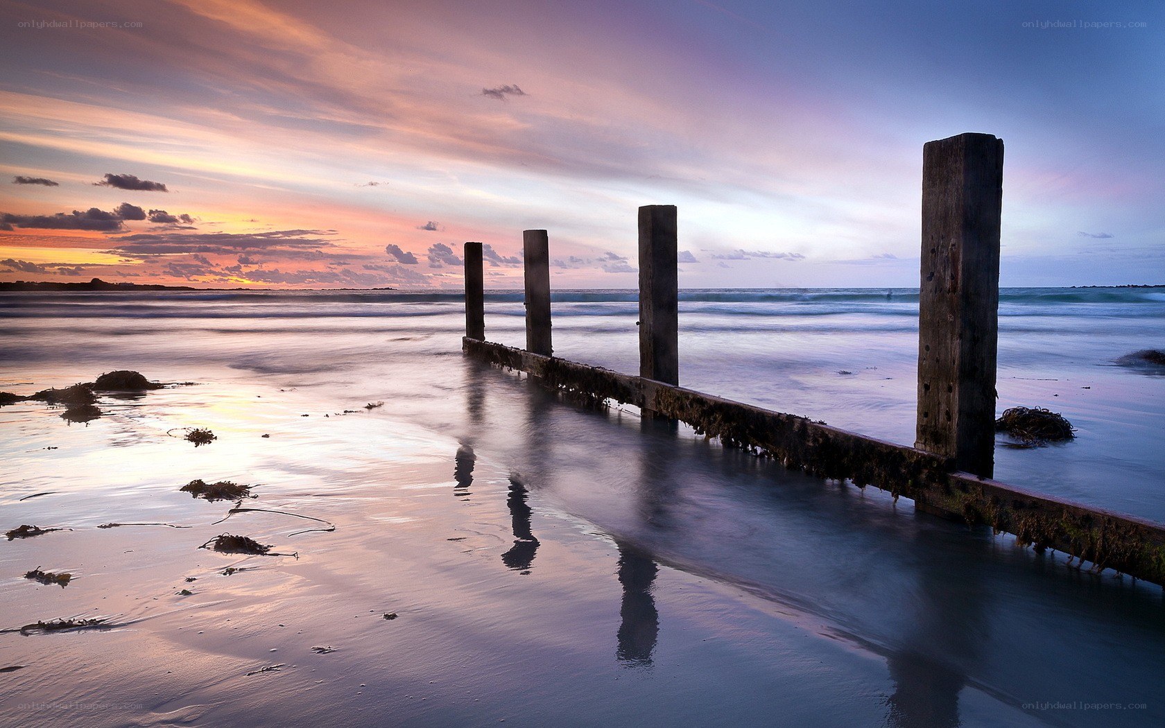 sunset at the beach with wooden posts