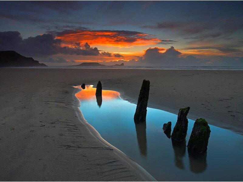 Sunset at the beach with wooden posts
