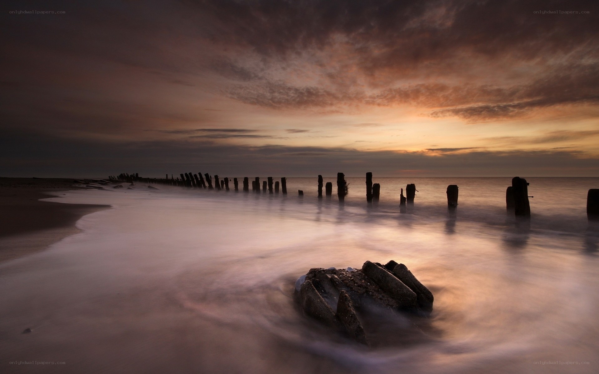 Sunset at the beach with wooden posts