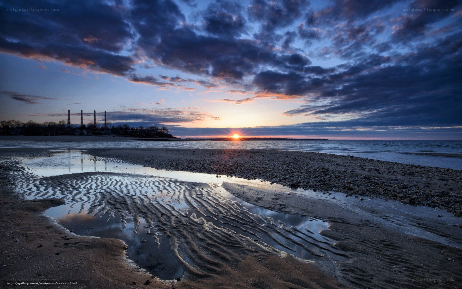 Sunset over a beach with industrial background