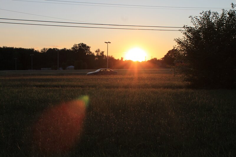Sunset over a field with car