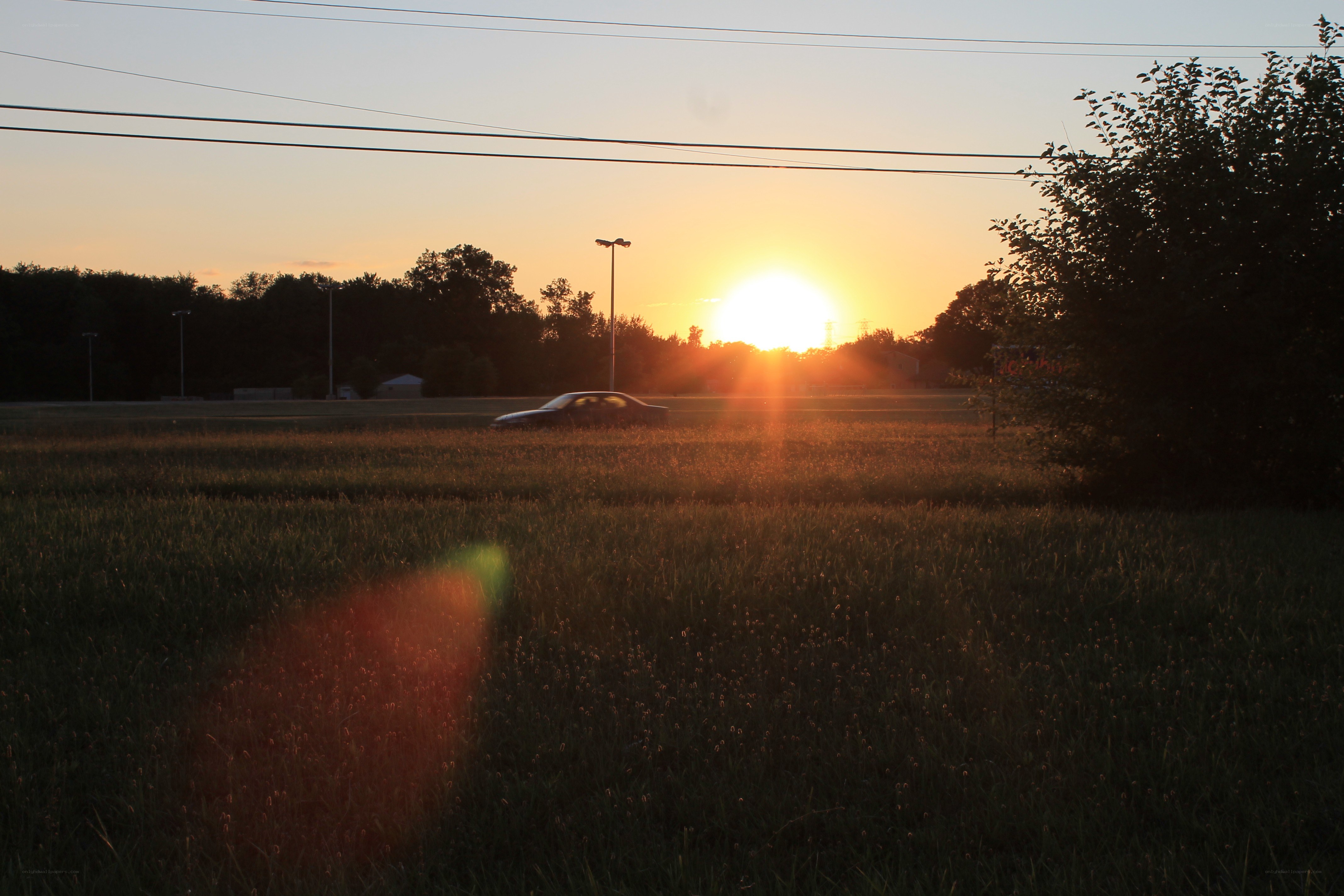 Sunset over a field with car
