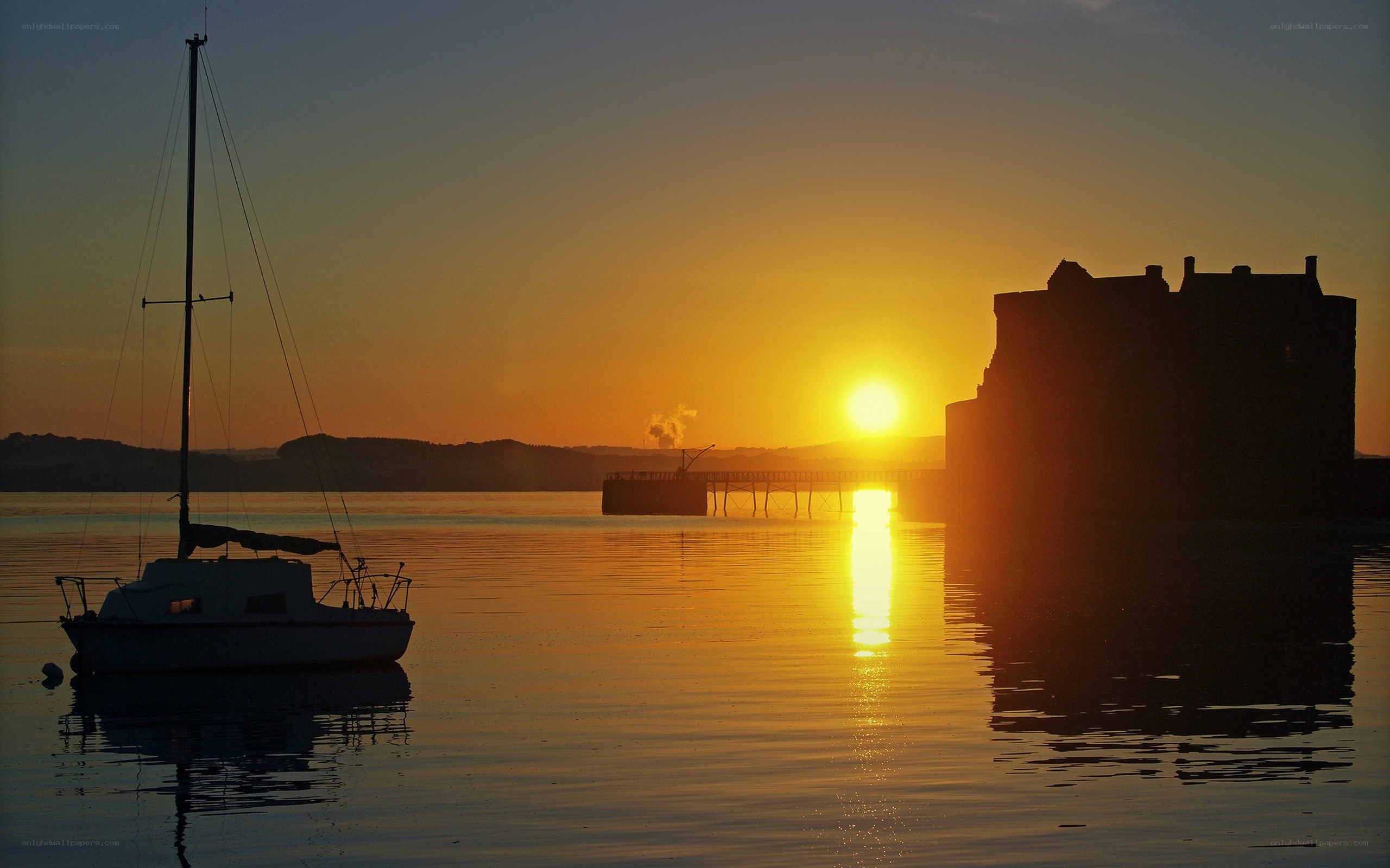 Sunset over a harbor with sailboat