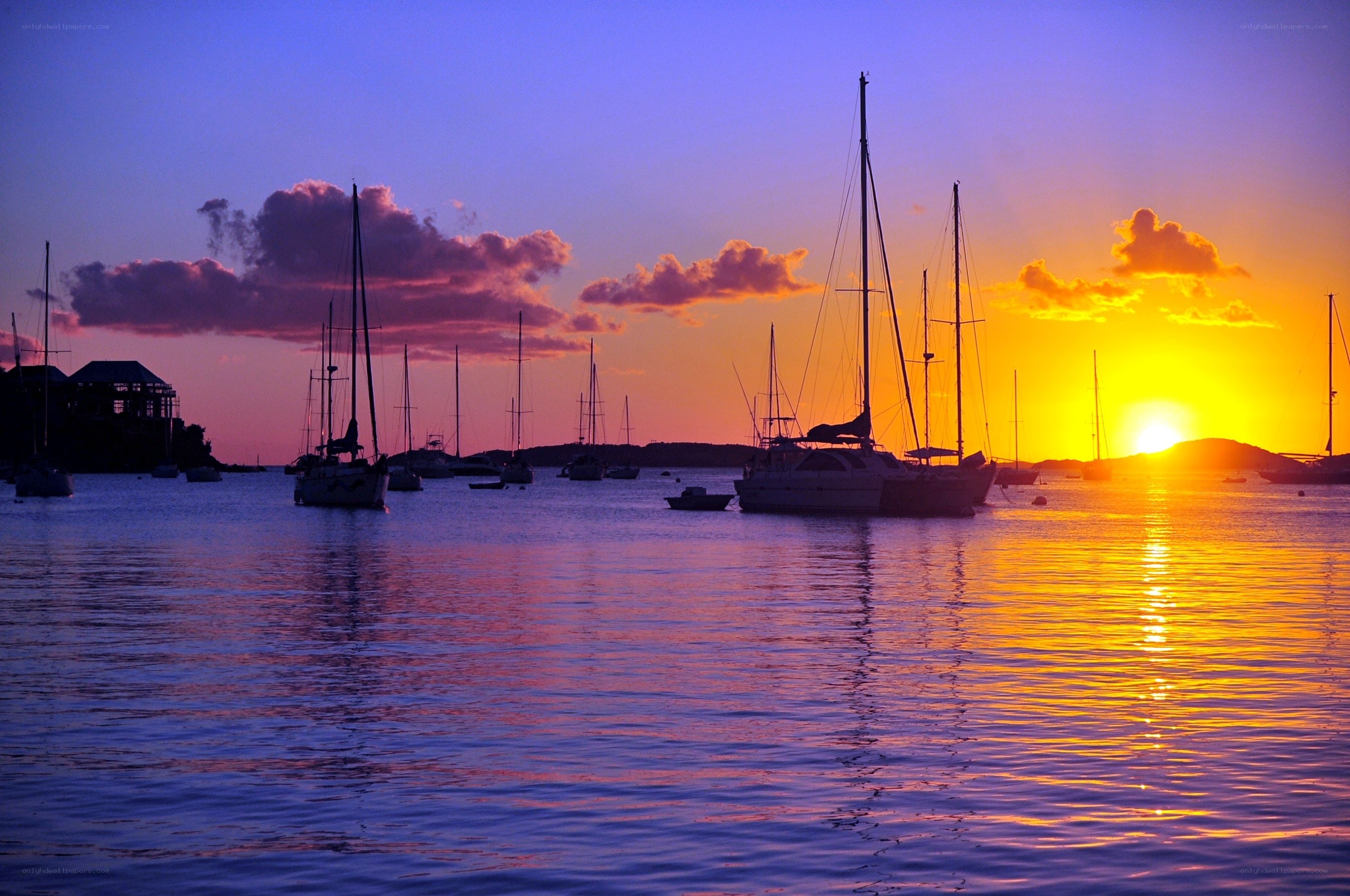 Sunset over a harbor with sailboats