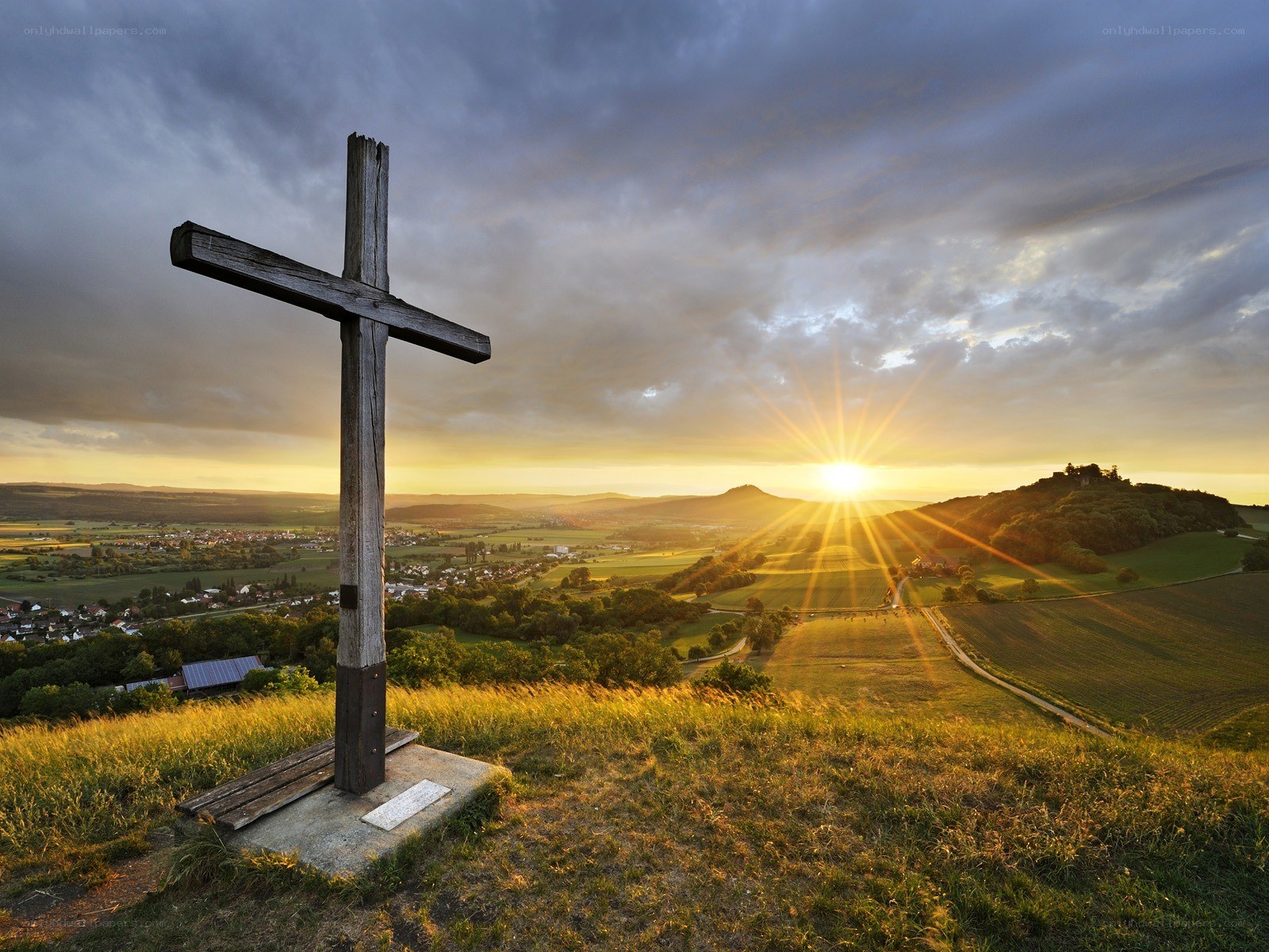 Sunset over a hill with a cross