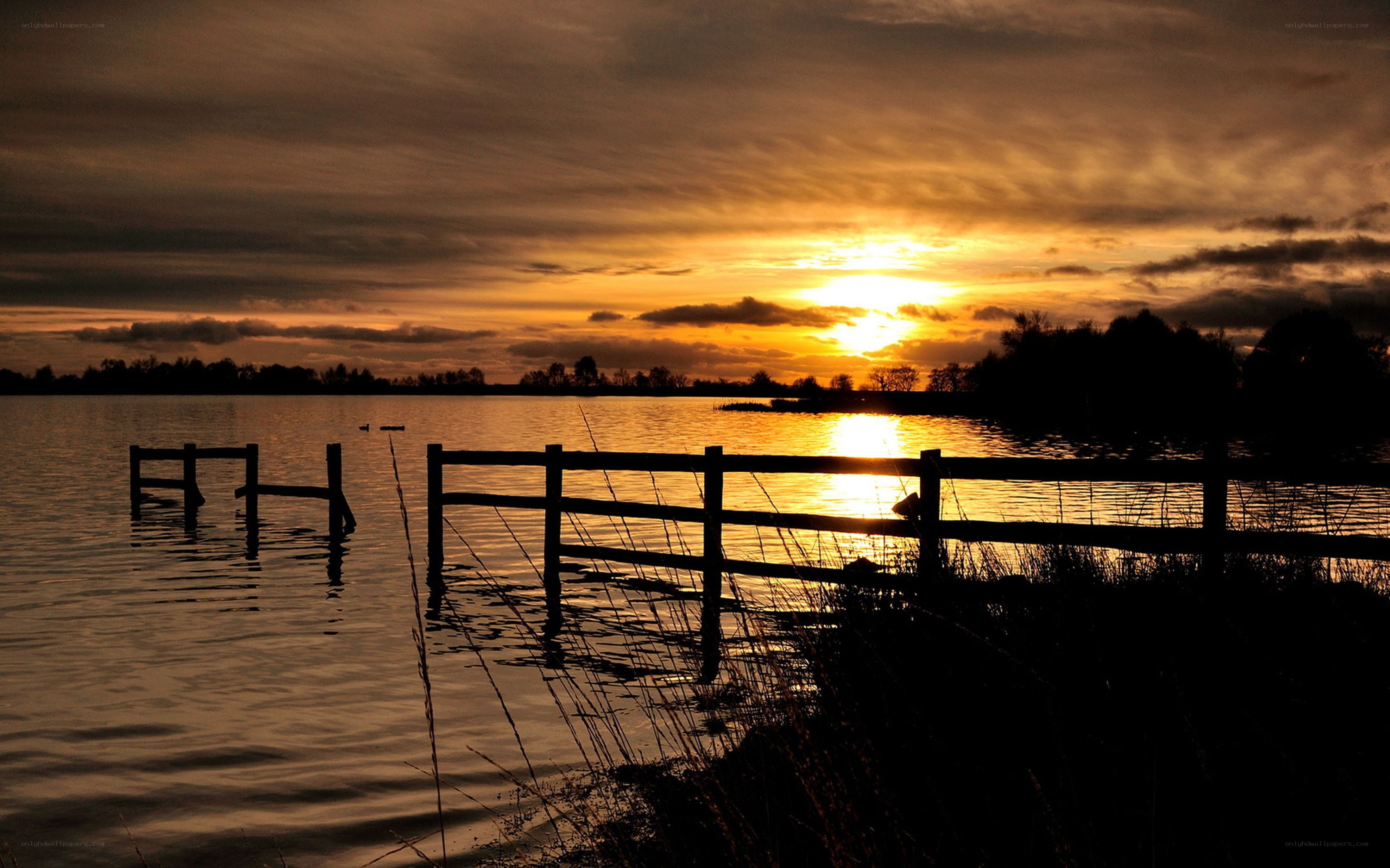 Sunset over a lake with fence