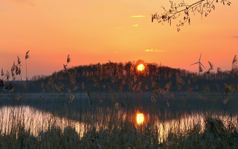 Sunset over a lake with wind turbine