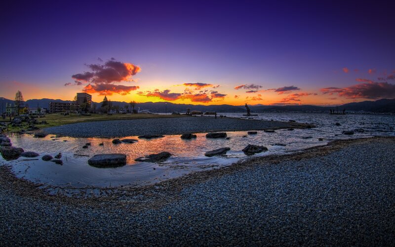 Sunset over a lakeside pebble beach