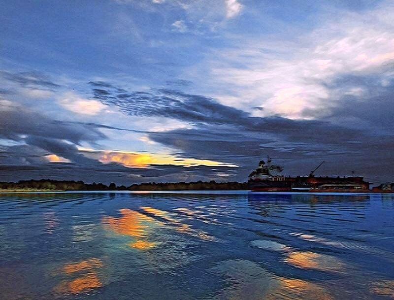 Sunset over a river with a ship
