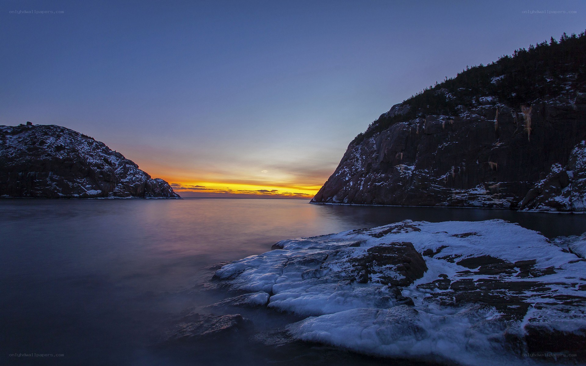 Sunset over a snowy coastal inlet