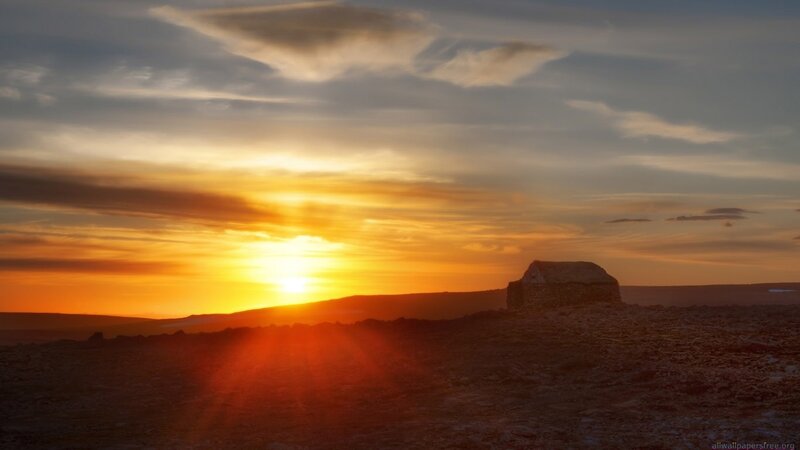 sunset over a stone hut