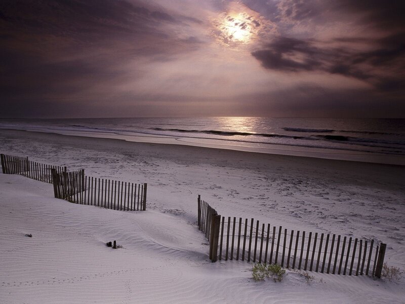 sunset over beach with fences
