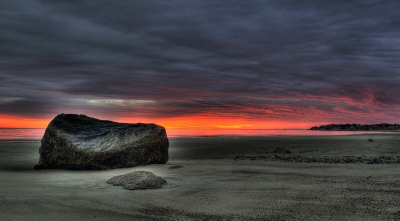 Sunset over beach with large rock
