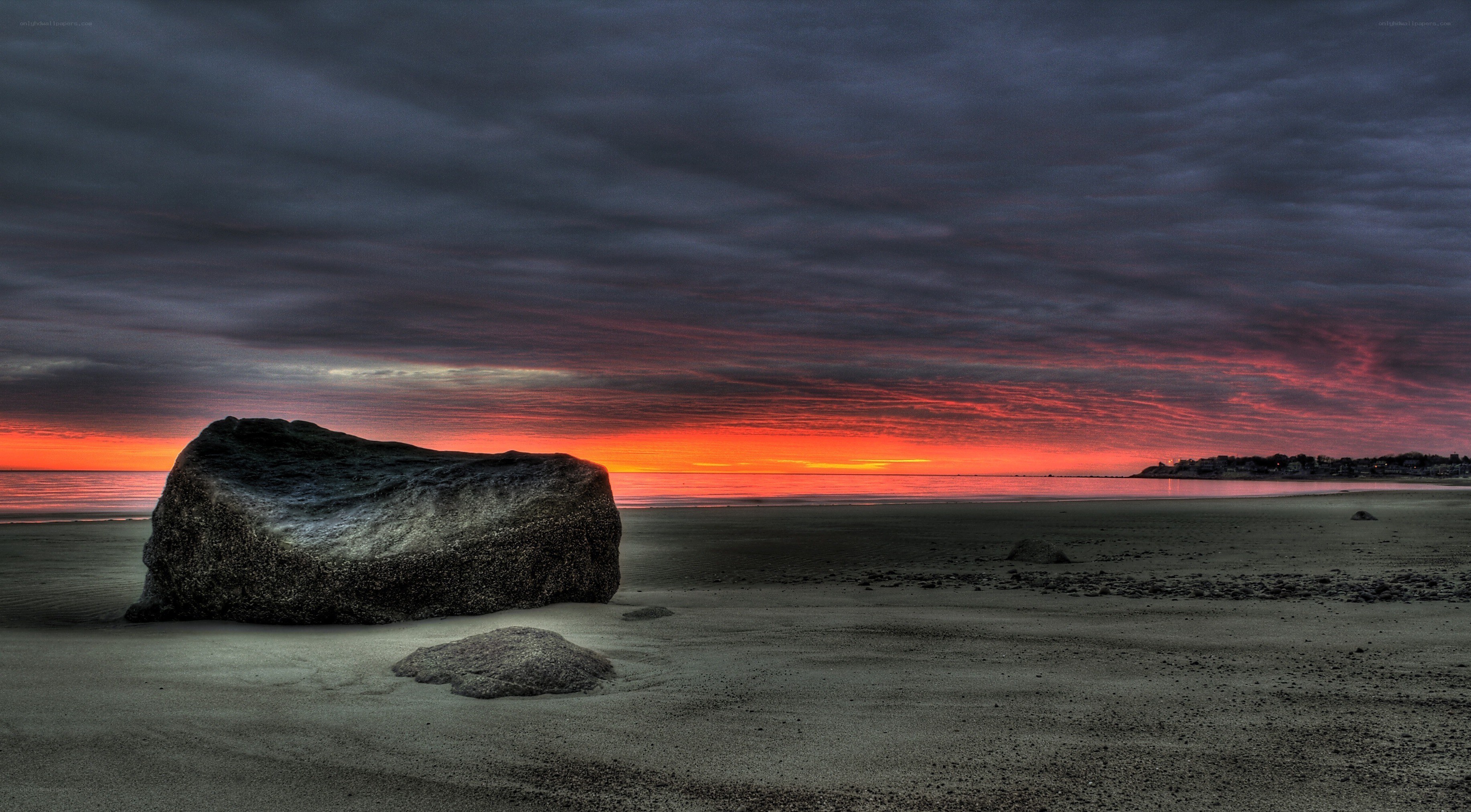 Sunset over beach with large rock