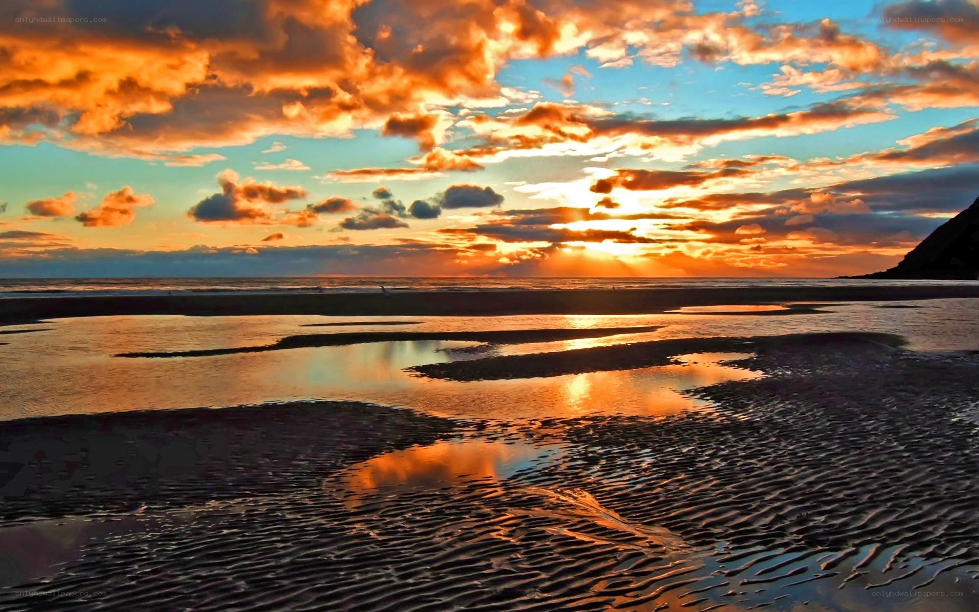Sunset over beach with rippled sand