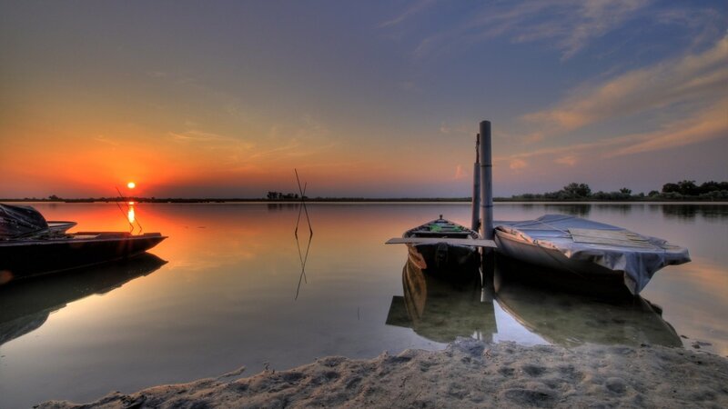 Sunset over calm lake with boats