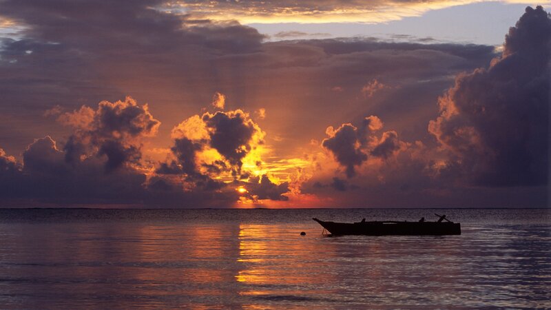 Sunset over calm ocean with boat