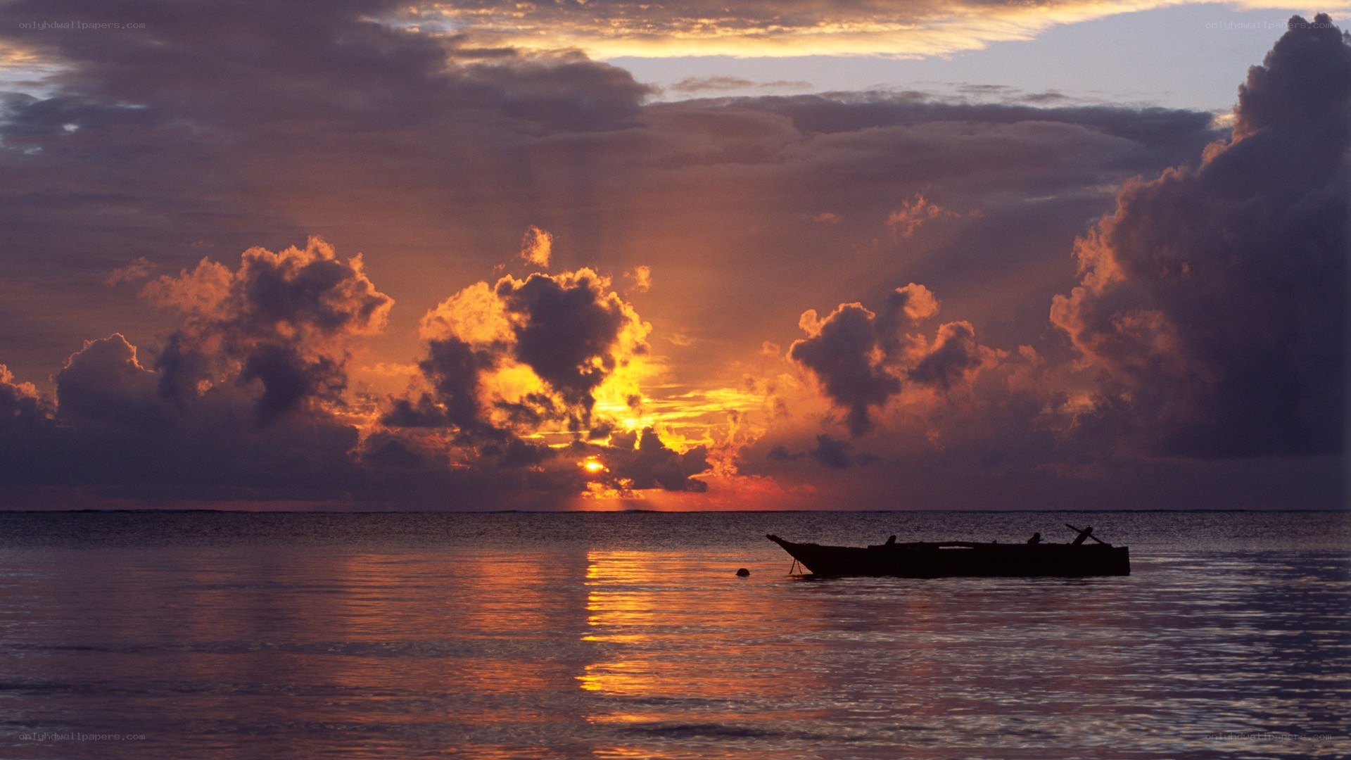 Sunset over calm ocean with boat