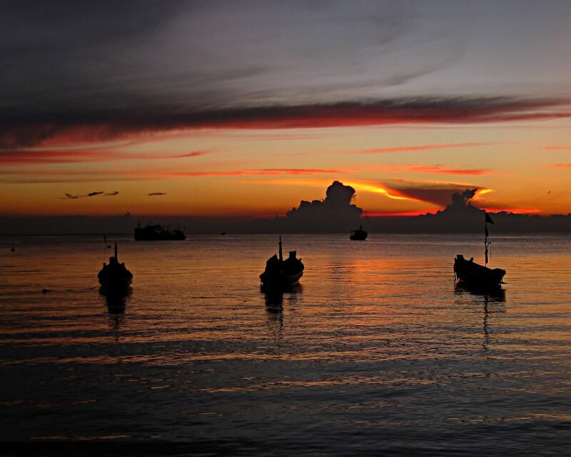 Sunset over calm sea with boats