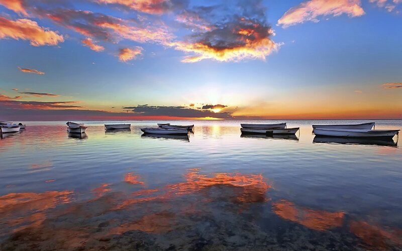 Sunset over calm sea with boats