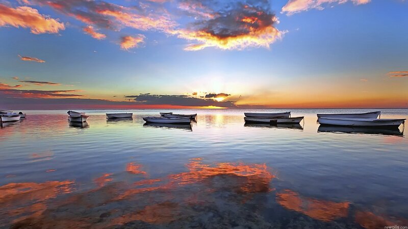 Sunset over calm sea with boats