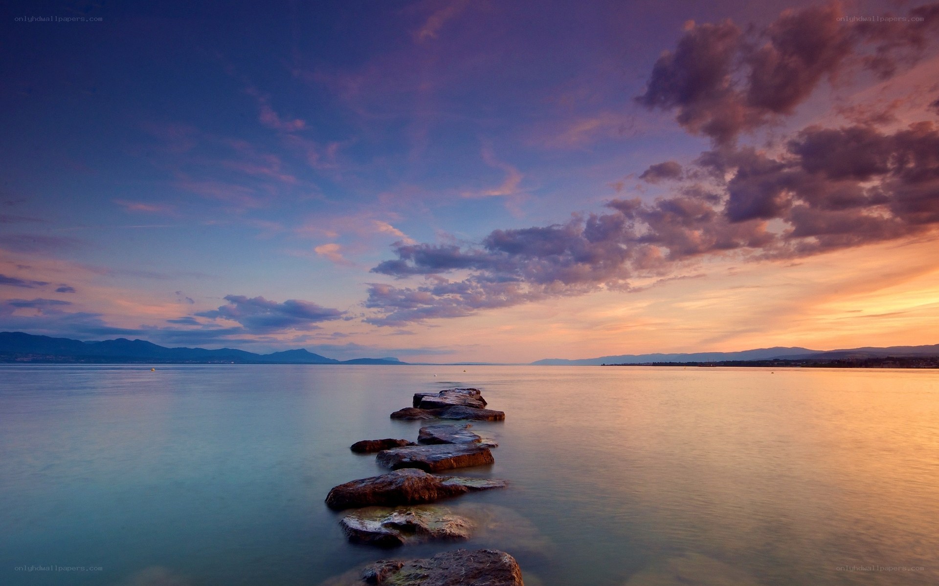 Sunset over calm sea with stone path