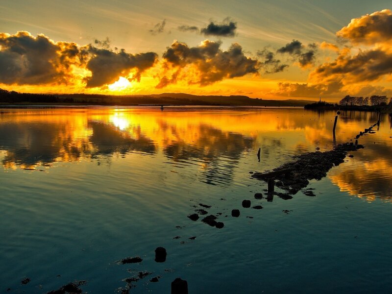 Sunset over Calm Water — Orange, Serene, Photograph, Clouds, Reflection, Wooden Posts