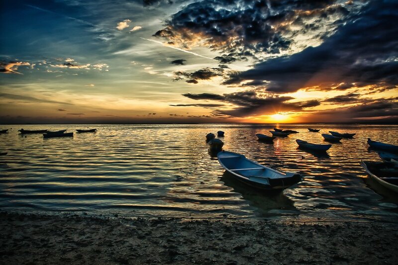 Sunset over calm water with boats
