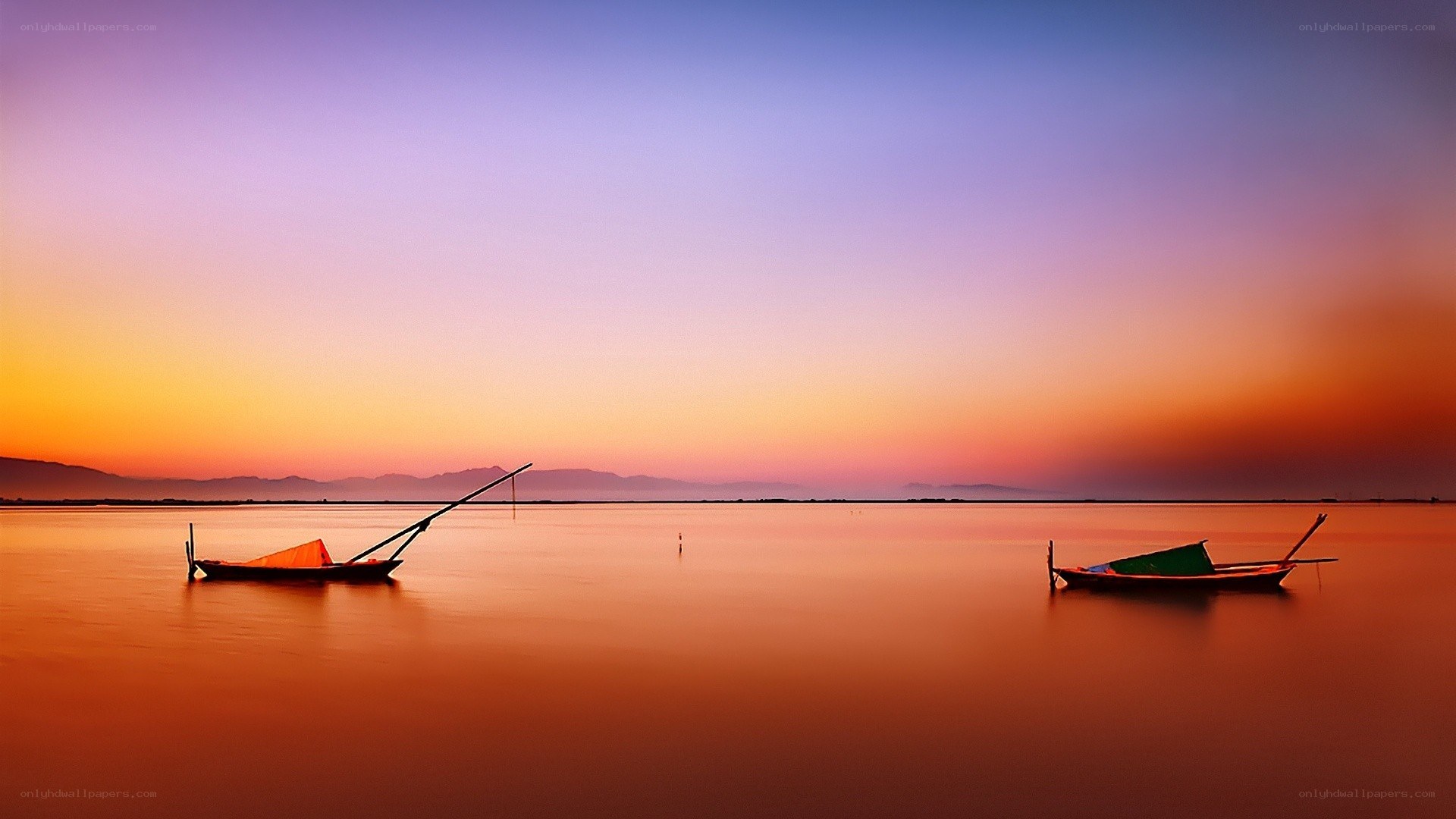 Sunset over calm water with boats
