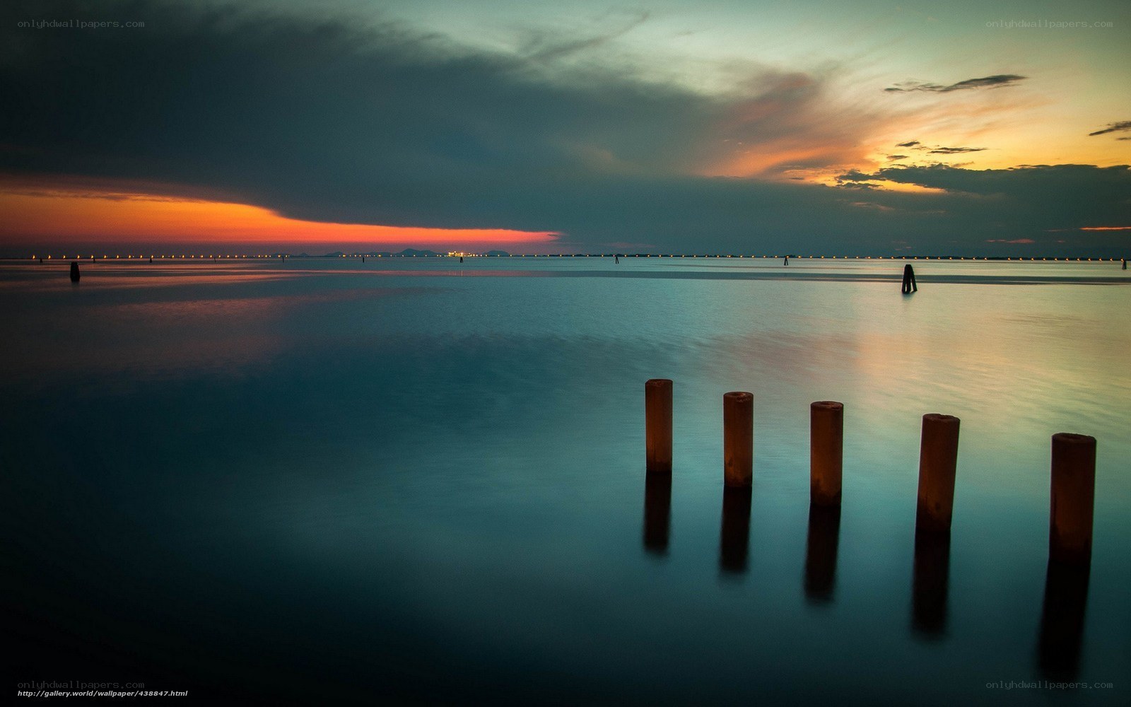 Sunset over calm water with pilings