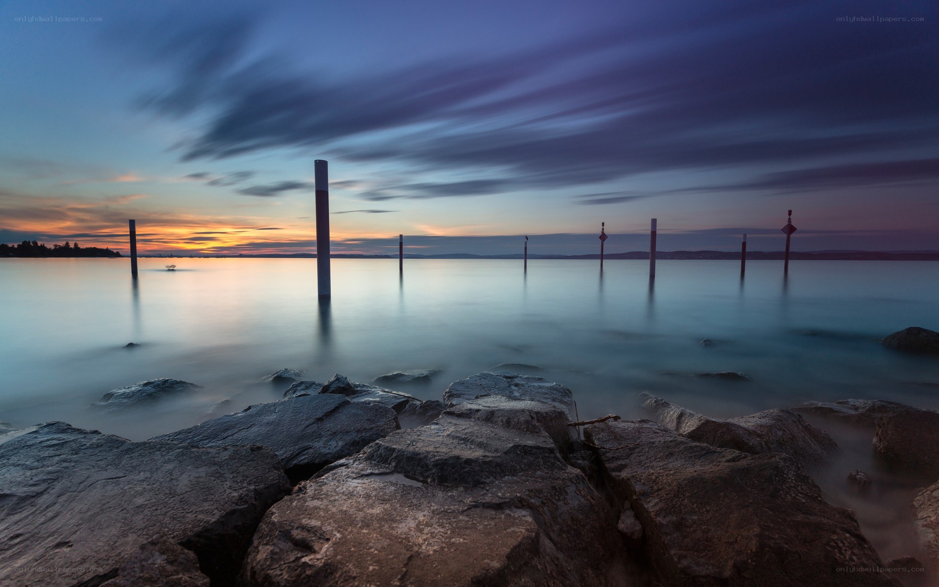 Sunset over calm water with rocks