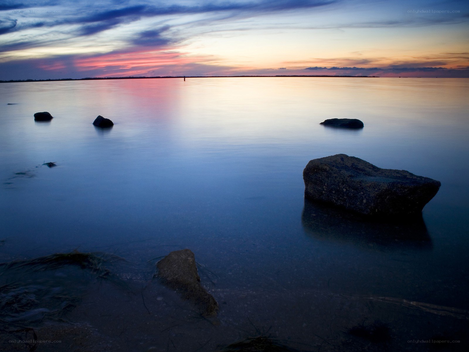 Sunset over calm water with rocks