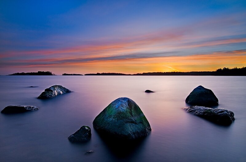 Sunset over calm water with rocks