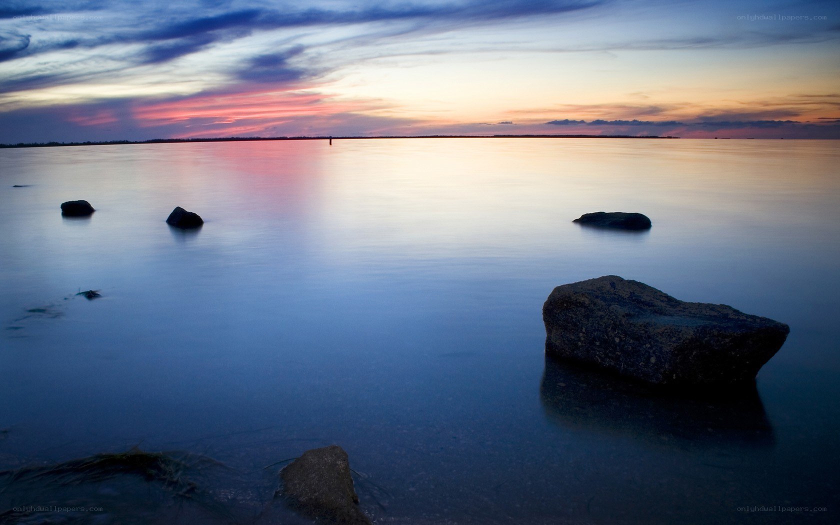 Sunset over calm water with rocks