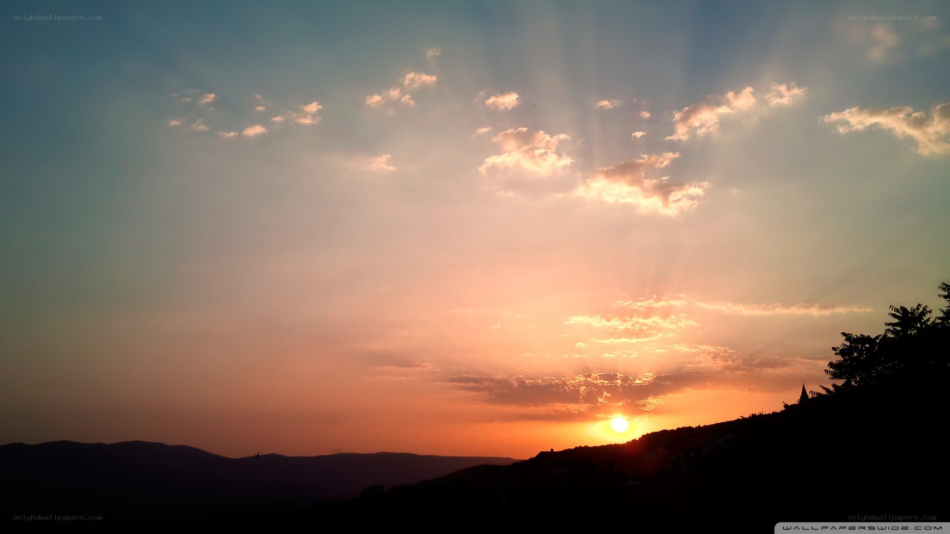 Sunset over hills with sunbeams