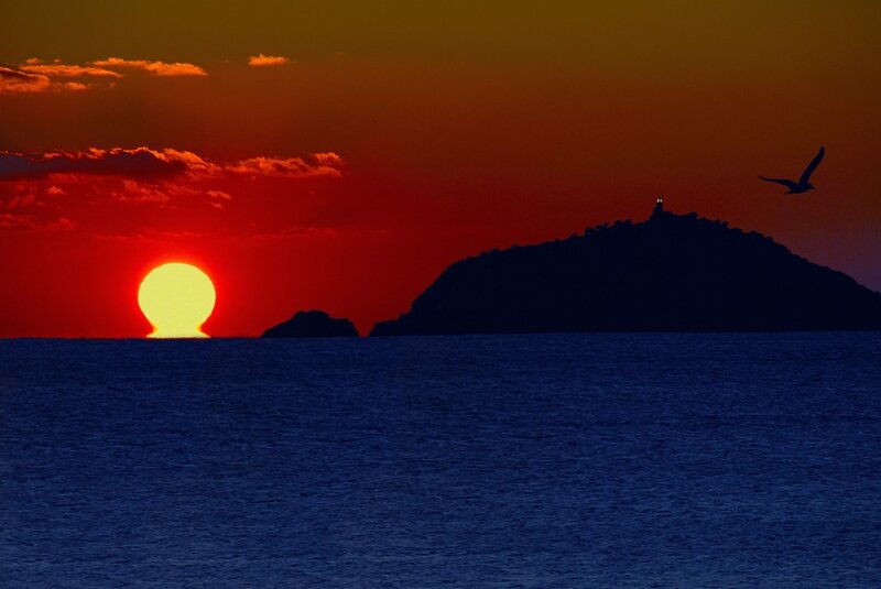 Sunset over island with lighthouse