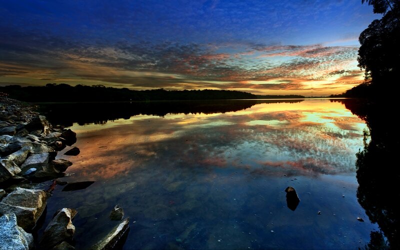 Sunset over Lake — Blue, Serene, Photograph, Rocks, Trees, Sky, Orange