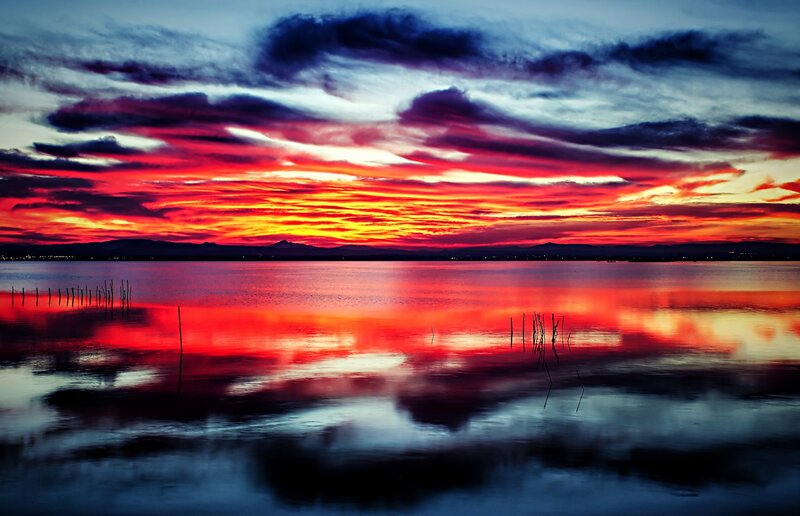 Sunset over Lake — Red, Dramatic, Photograph, Clouds, Mountains, Wooden Poles