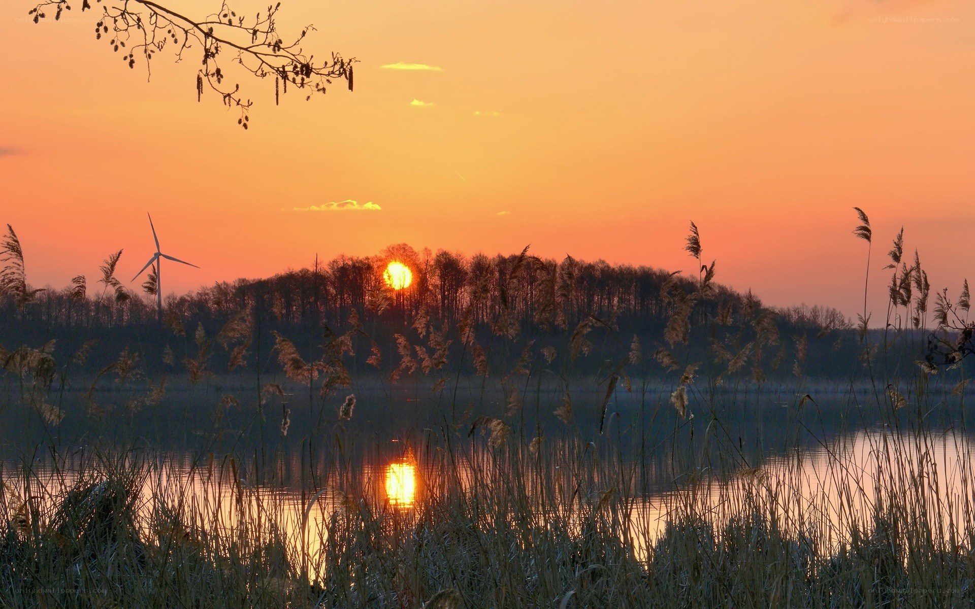 sunset over lake with wind turbine