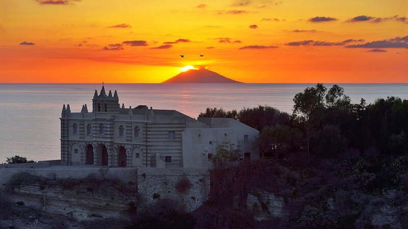 Sunset over Mount Etna and a coastal church