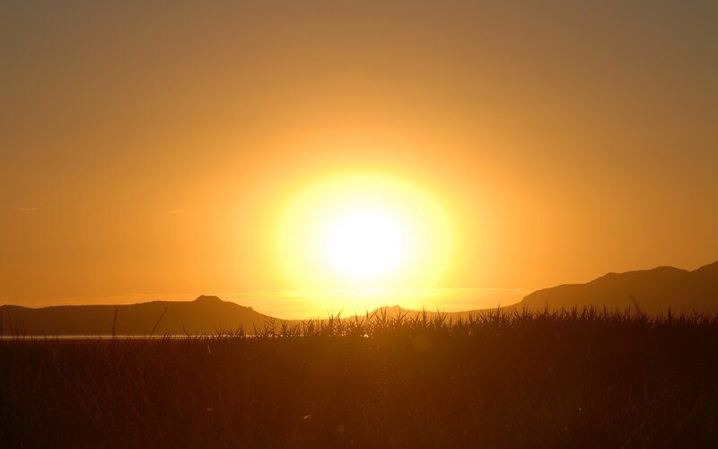 Sunset over mountains and field