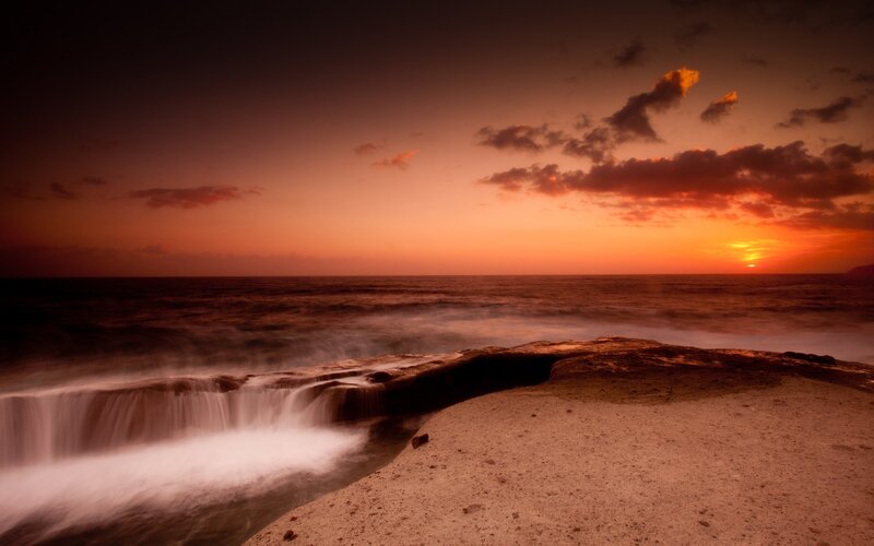 Sunset over ocean waterfall