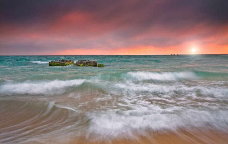 Sunset over ocean with rocks
